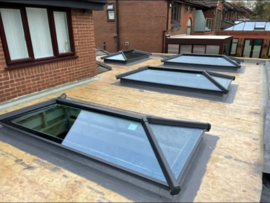 Four aluminium roof lanterns fitted across one large flat roof mid-build, deck still exposed