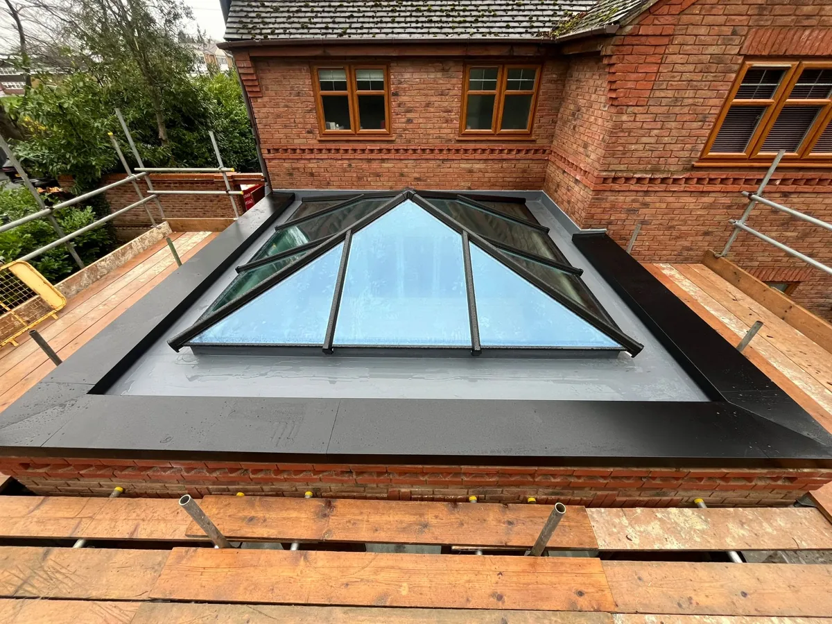 Wide view of a finished anthracite roof lantern on a brick upstand with scaffolding around the extension